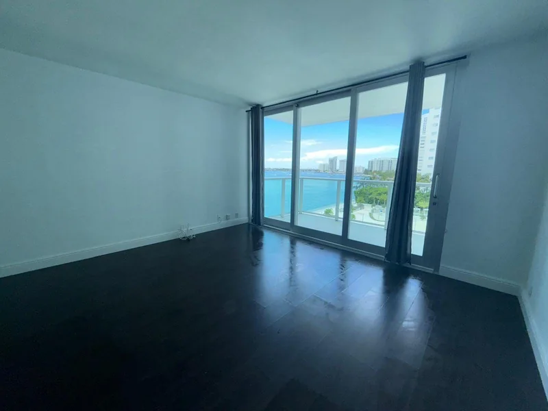 Empty room with wood floors, large windows and a water view