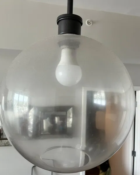 Before: glass pendant light with a cloudy, dusty surface around a white bulb.