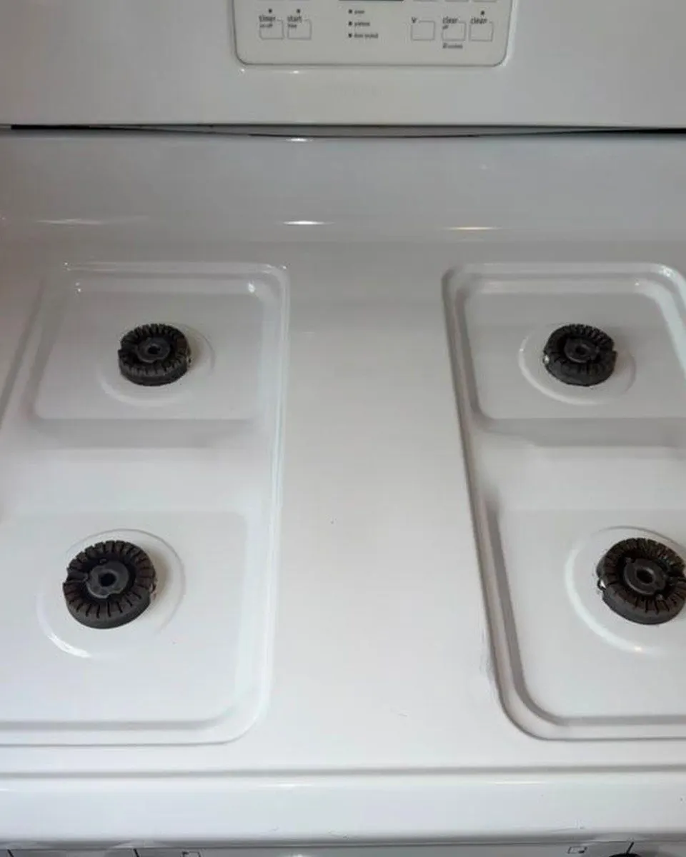 White gas stovetop with four exposed burners.
