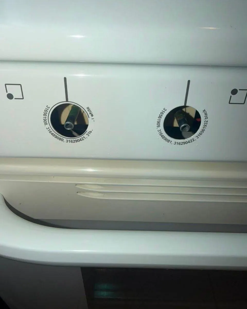White oven control panel and door handle with two control knobs removed.