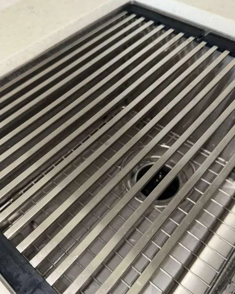 After: stainless steel kitchen sink with a metal drying rack across the basin.