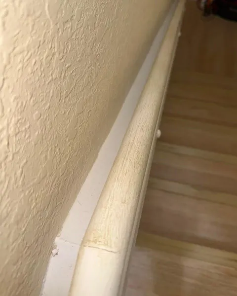 Before: white stair handrail with visible surface marks above wooden steps.
