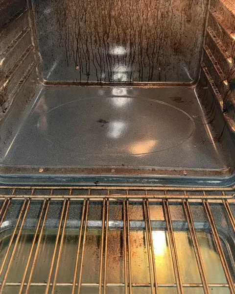 Before: oven interior with dark grease streaks on the back wall and door glass.