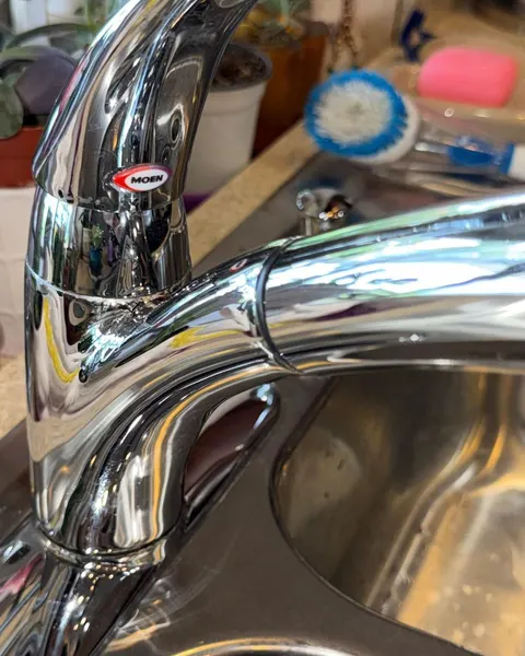 After: chrome kitchen faucet above a stainless steel sink.